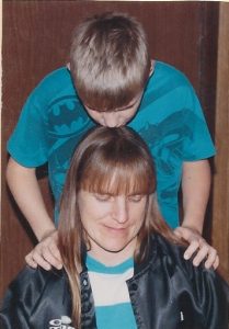 A young Michael Politte kisses his mother, Rita Politte, on top of her head while standing over her.